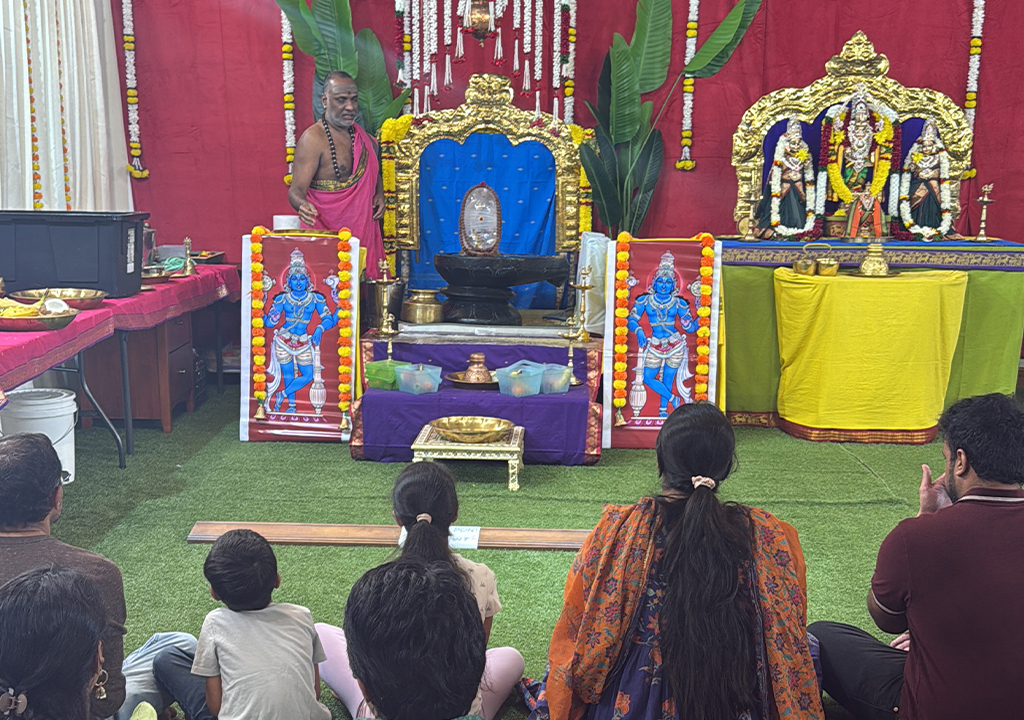 Priest performing Abhishekam at Hari Hara Kshethram while devotees sit in prayer during a sacred temple celebration.